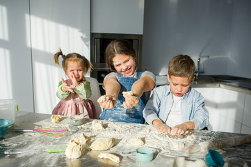 Three children prepare something from the dough.