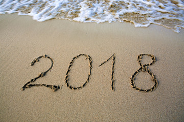 Year 2018 written at the caribbean sand beach with sea wave .