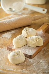Handgemachte Tortelloni auf Holzbrett mit Mehl und Nudelholz