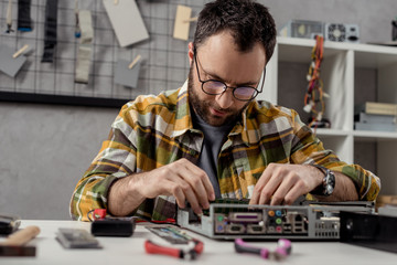 man looking down while fixing broken computer