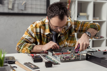 repairman using tongs while fixing broken pc