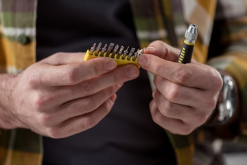 cropped image of hands holding screwdriver and its attachments