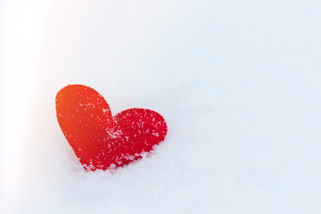 red felt heart figure on snow, winter day with sun glare