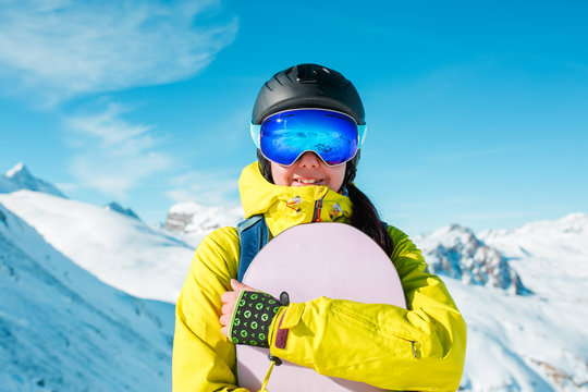 Photo of sporty woman wearing helmet and snowboarding against background of snowy hills