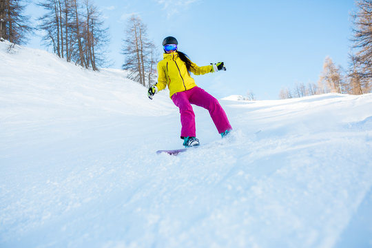 Photo of sports woman wearing helmet and snowboarding mask from snowy slope with trees