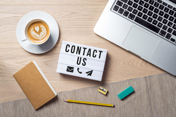 Contact us writing in lightbox lying on desk as flatlay - 192584899