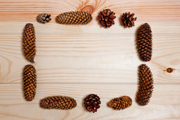 Frame of pine and spruce cones on a wooden surface