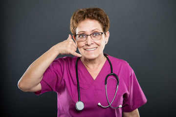 Portrait of senior lady doctor showing calling gesture
