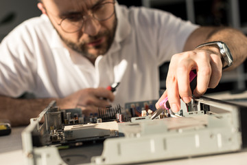 man using tongs while fixing broken pc