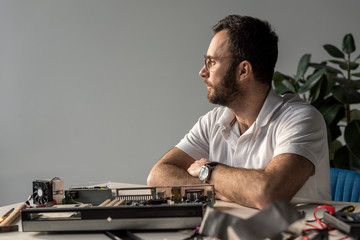 man with hands on table against pc looking away