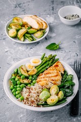 Healthy grilled vegetables buddha bowl with chicken and quinoa, spinach, egg, zucchini, asparagus, Brussels sprouts and green peas