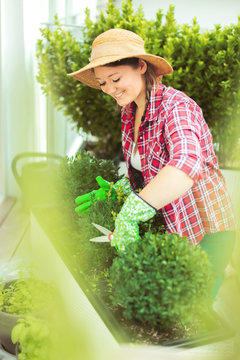 Fröhliche Frau im Garten beim Pflanzenpflege