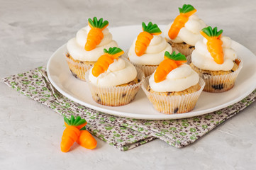 Vanilla cupcakes with chocolate chips and cream cheese frosting decorated with carrot marmalade.