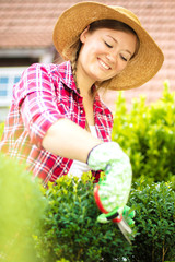 Fröhliche Frau im Garten beim Pflanzenpflege