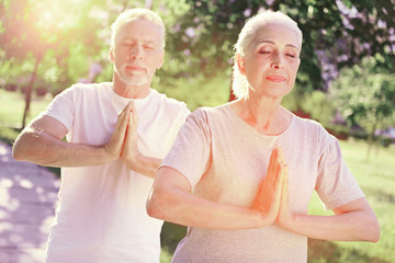 Obraz premium Being concentrated. Close up of peaceful family keeping palms together while standing with eyes closed and meditating