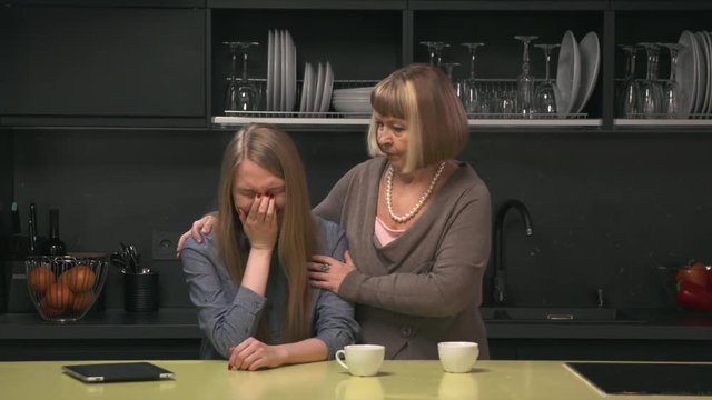 Adult daughter crying and senior mother trying to calm her
