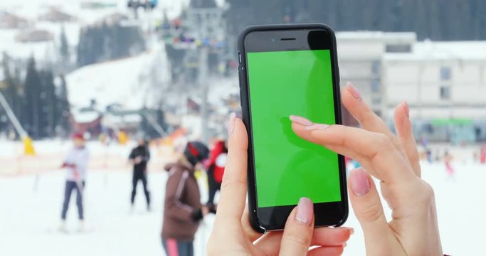 closeup girl using mobile smart phone take photography photo tap scroll pointing finger blank green screen chromakey mockup free people skiing background winter mountains resort recreational business
