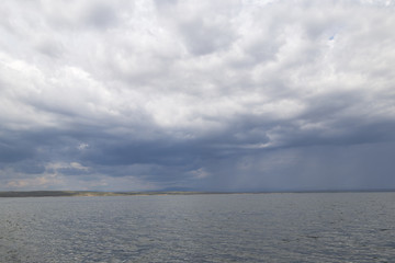 A large reservoir ( lake ) in Kazakhstan under a cloudy and rainy sky