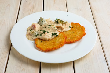 Potato pancakes with flour sauce and pickled cucumber and sausage
