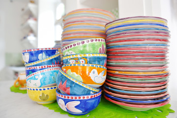 Stack of colorful hand painted ceramic bowls and plates - Italian handcraft