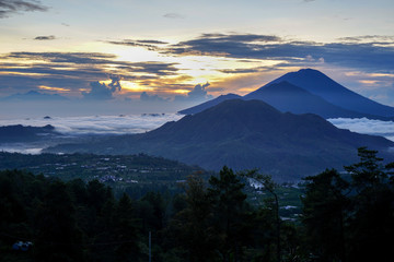 Fototapeta na wymiar Dawn overlooking the 3 mountains at the same time, Agun, Batur at Bali island. A small smoke from the volcano. Side view with copy space