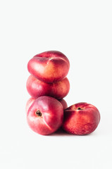 Fototapeta na wymiar Stack of fresh flat donut nectarines, red saturn nectarines or ripe fuzzless vineyard peaches on white background