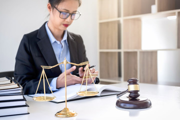 Legal law, advice and justice concept, Professional Female lawyers working on courtroom sitting at the table and signing papers with gavel and Scales of justice