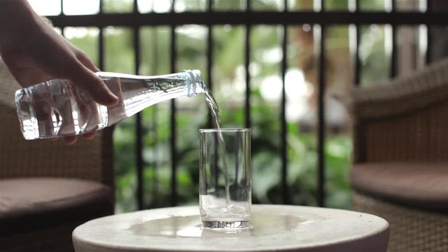 close-up. man pours clean water from a bottle into a glass