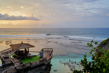 Multicolored sunset on Uluwatu island of Bali. Large clouds hung over the ocean. The house stands on the cliff face. Side view with copy space