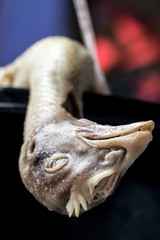 Poultry ready to prepare food in the street restaurant, Thailand. The plucked hen lies in a pot with her head hanging down.