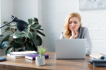 sad businesswoman looking at laptop in office