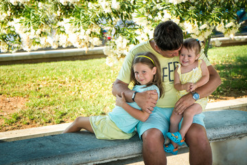 Fototapeta na wymiar Portrait of a father and two small daughters in a summer park
