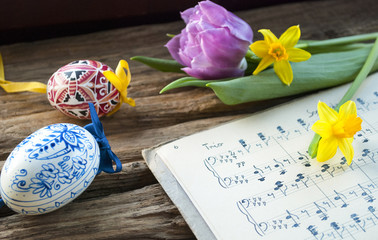 Alte handgeschriebene Musiknoten mit bemaltem Osterei, lila Tulpe und Narzissen, Narcissus...