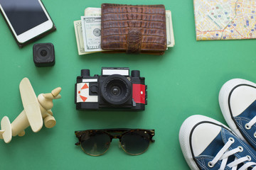 Vacation planning. Green one-color background with tourist's accessories outfit, top view. Travel or tourism concept.