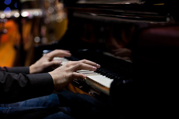 Obraz premium The hands of a musician playing the piano closeup in dark tones