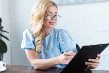 beautiful businesswoman looking at clipboard in office