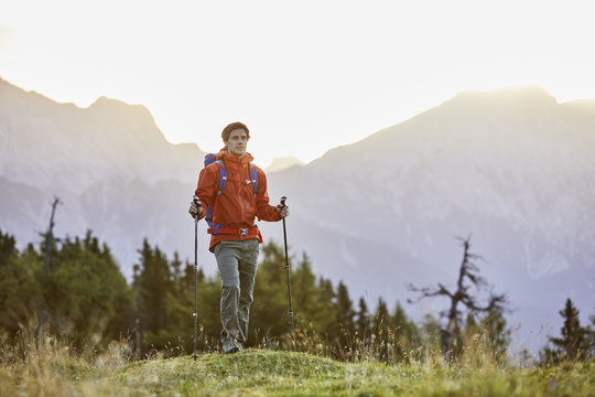 Austria, Tyrol, Mieming Plateau, portrait of hiker on alpine meadow at sunrise