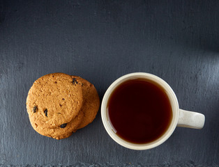 Top view on a cup of tea and cookies isolated on a dark background, close-up