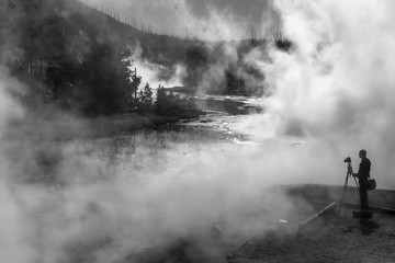 Photographer taking pictures of steamy hot spring in Yellowstone National Park