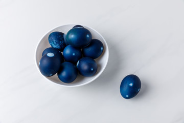 blue painted easter eggs in bowl on white surface