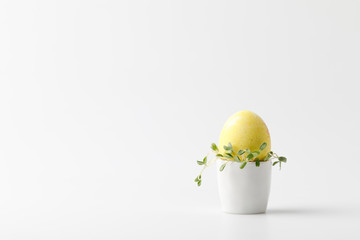 yellow painted easter egg in egg stand on white