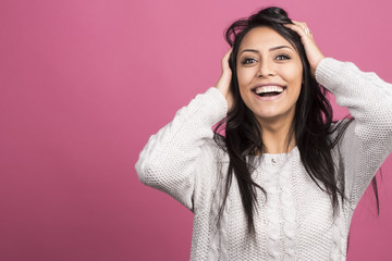 Terrific brunette model expressing surprised emotions while holding her head on indoor photoshoot. Stylish dark hair woman having fun in pink studio