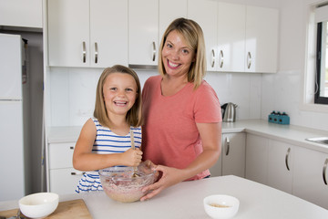 Obraz na płótnie Canvas young mother and sweet little daughter baking together happy at home kitchen in family lifestyle concept