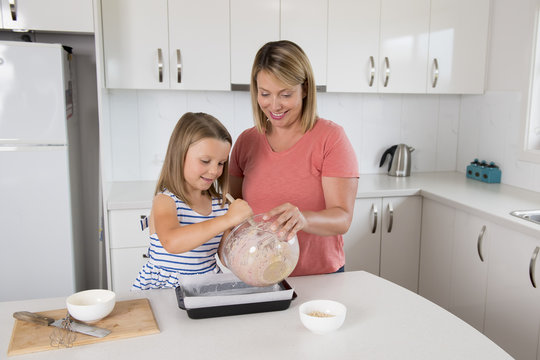 young mother and sweet little daughter baking together happy at home kitchen in family lifestyle concept