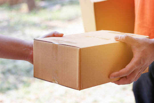 Customer Signing Document And Receiving The Parcel From Delivery Man.