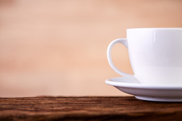Side close up view of half a tea cup and saucer on vintage table background, indoors.