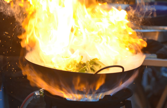'Stir fried swamp cabbage', abstract blur image of flame on a burning pan when thai chef cooking a swamp cabbage/water spinach, cooking style, art of food cooking, thai food, food style, burning pan