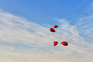 four heart balloons in blue cloudy sky