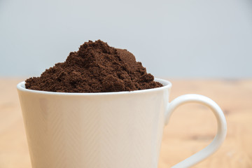 Coffee grounds in a white cup on  a wooden table for breakfast