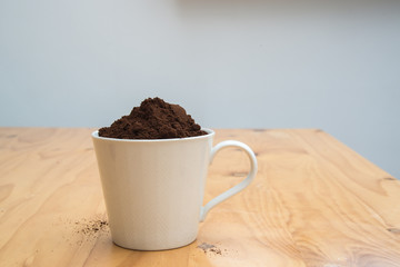 Coffee grounds in a white cup on  a wooden table for breakfast